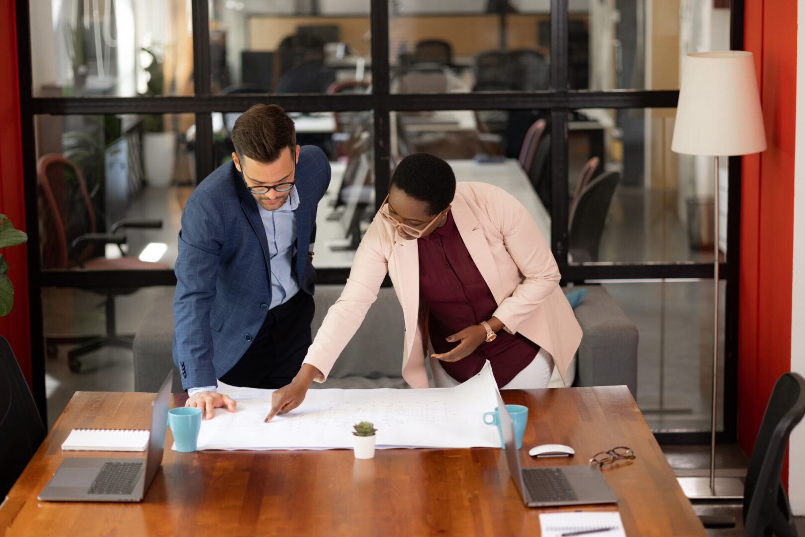 Two colleagues reviewing a blueprint together.